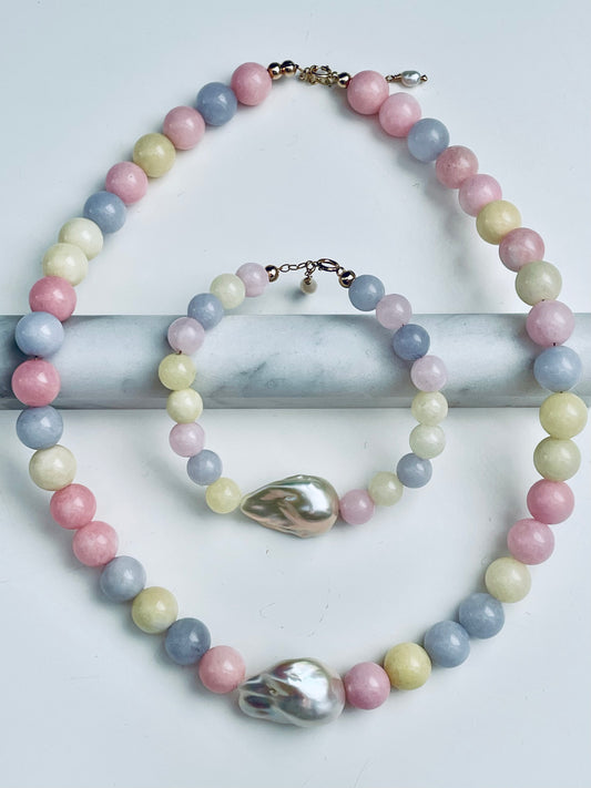 Pastel beaded necklace with large shell pendants on a marble surface