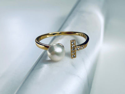 Gold ring with a pearl on a light gray background